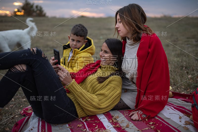 一个男孩噘嘴，因为他的妈妈正在看她的手机库存照片