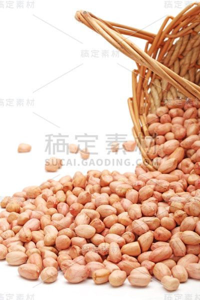 去皮的花生从篮子里散落在白色的背景上