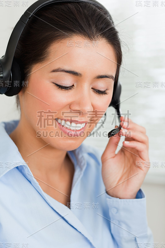 一个迷人的女人的肖像与耳机帮助客户而坐