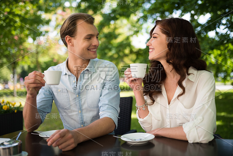 一对夫妇坐在户外喝着卡布奇诺