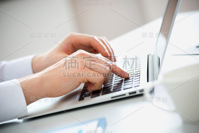 商人在笔记本电脑上打字的手的特写。