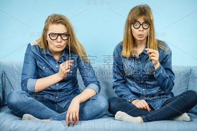 两个开心的女人拿着假眼镜