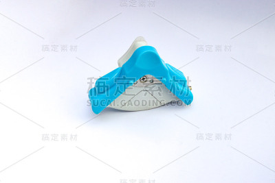 蓝色和白色的角刀圆冲头，用于切割卡片相纸。孤立在白色背景上。