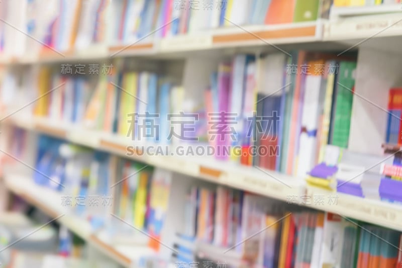 模糊的学校图书馆的书架上有彩色的书，小册子和教科书。教育、学校、学习理念。对抽象的背景