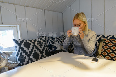 年轻漂亮的女人在家里喝咖啡