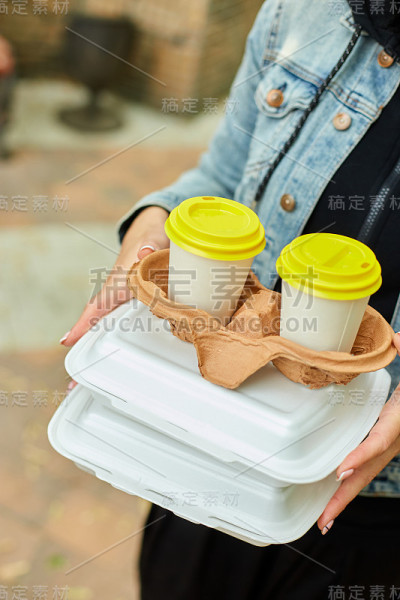 一个女人在公园里散步，手里拿着外卖和咖啡