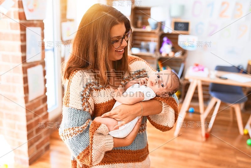 年轻漂亮的女人和她的孩子站在家里。母亲抱着新生儿