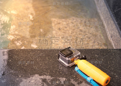 行动相机在防水的情况下和浮子抓地力在泳池边与阳光