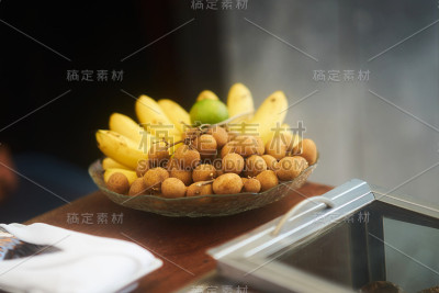 龙眼、香蕉、橘子放在玻璃碗上供食用
