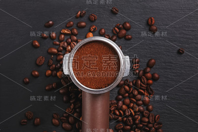 黑色背景上散落着烘培咖啡豆的咖啡滤嘴，