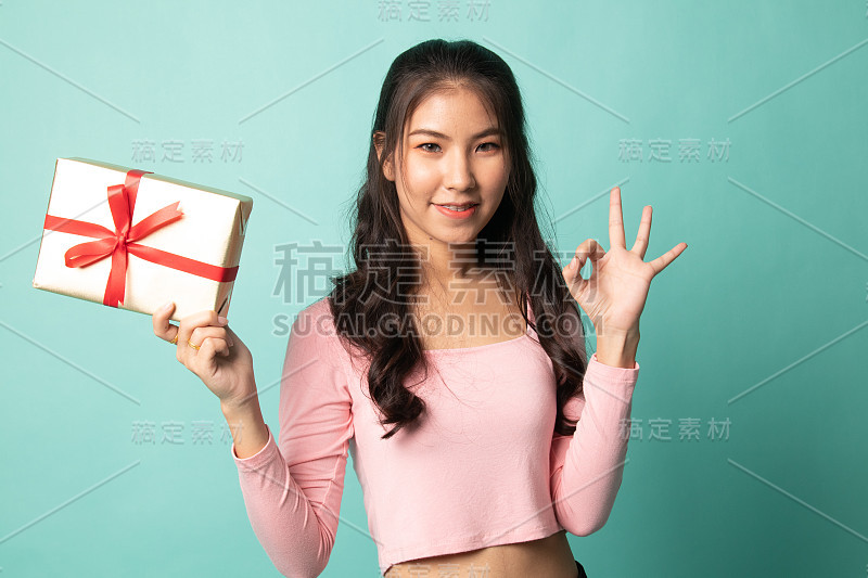 年轻的亚洲妇女显示OK与礼品盒。