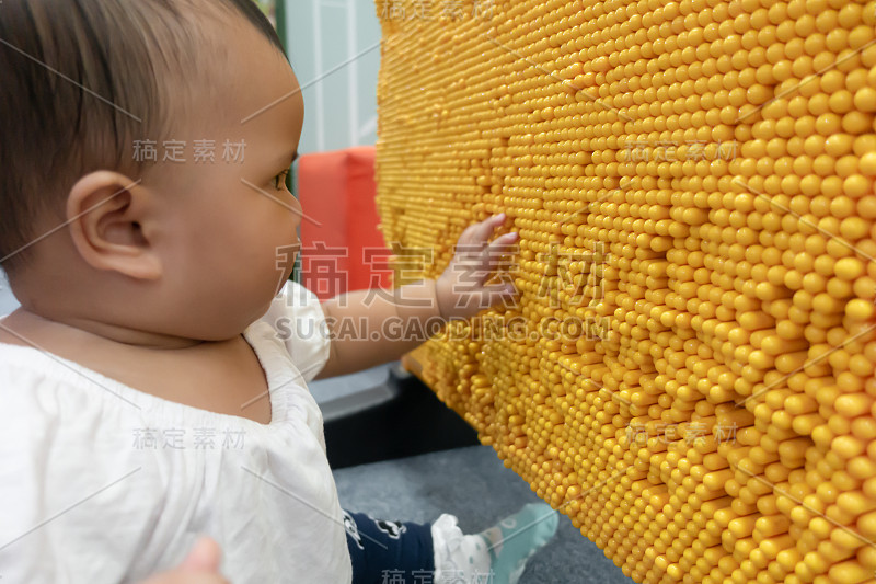 亚洲女婴在黄色大头针上制作手印玩具