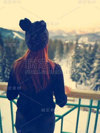 阳台上的女人。欣赏白雪覆盖的自然景观