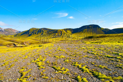 冰岛拉格维古尔徒步旅行路线沿途的冰岛高地上的绿色山丘和黑色岩石地面。阳光明媚的夏日拍摄