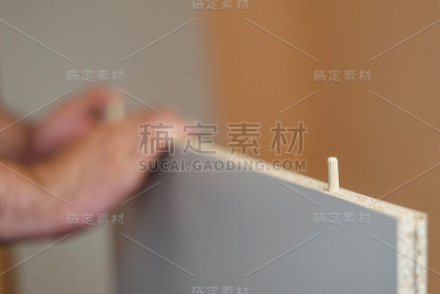 一名男子将家具销子插入白板上的一个洞中