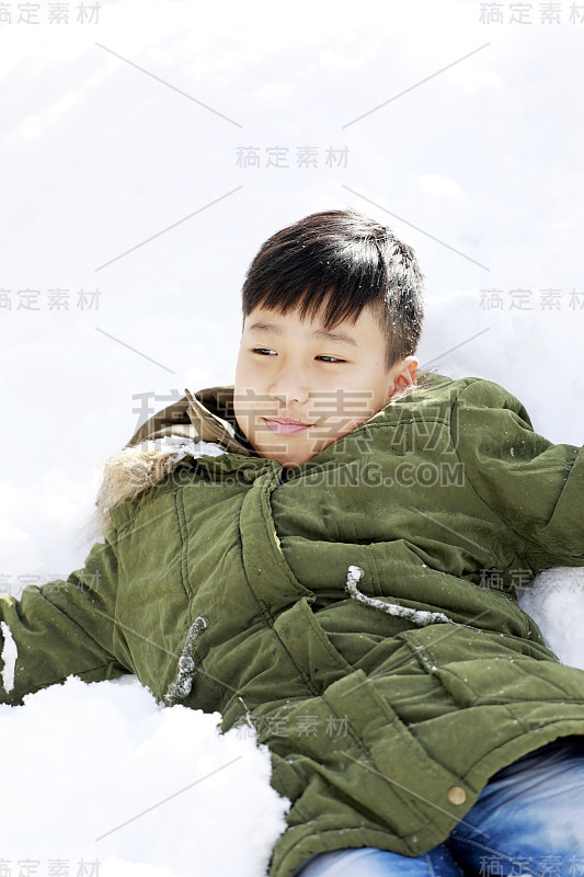 冬天，男孩躺在雪地上享受雪