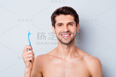 他的特写肖像，他漂亮的迷人的胡子，愉快的棕色头发的裸体的家伙手里拿着牙刷完美增强牙龈疗法孤立在浅白灰