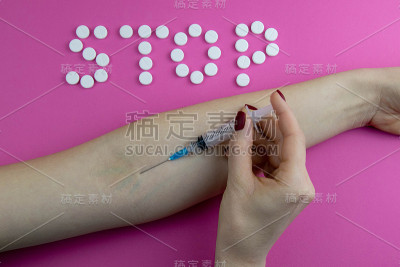 “停止”这个词是用药片和一只拿着注射器进行注射的手拼出来的