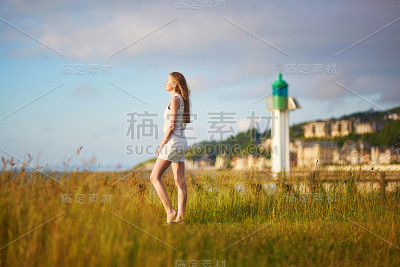 迪维尔灯塔附近草地上的日落女子