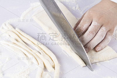 老妇人的手用刀切生面团