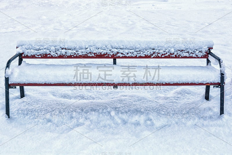 白雪覆盖的木凳在冬日公园里，以蓬松的白雪为背景