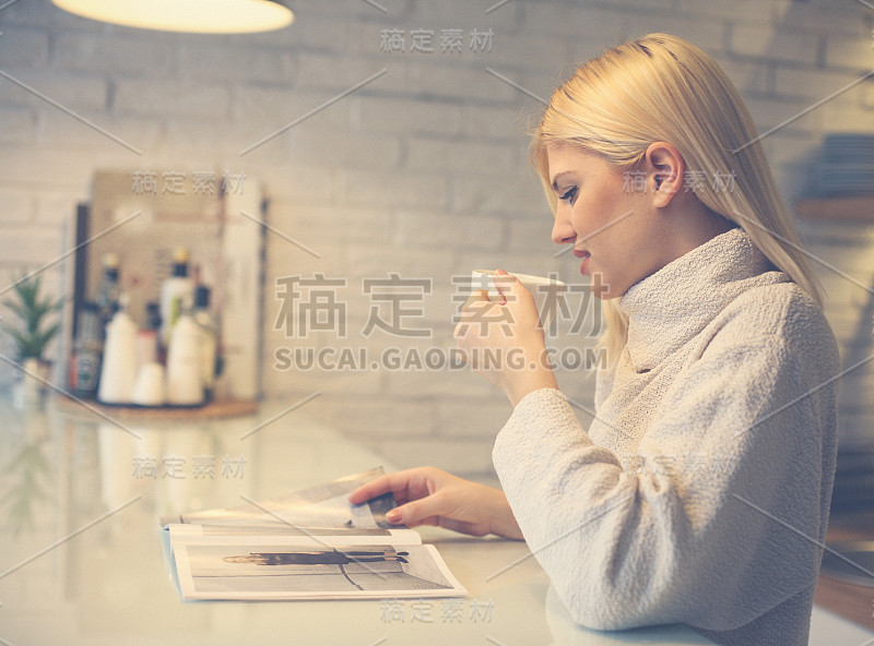 早上喝咖啡的金发女人。女人读报纸。