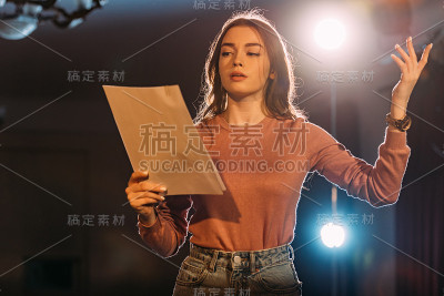 年轻女演员在剧院的舞台上阅读剧本