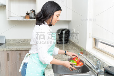美丽的家庭主妇在厨房清洁蔬菜