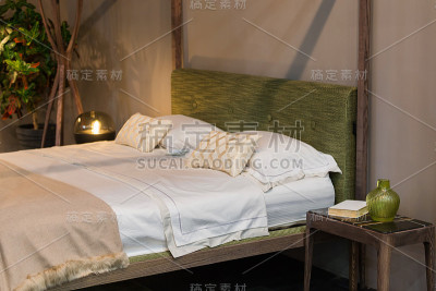 双人床，木质元素的卧室，大理石和木质床头柜，绿色花瓶，绿色头枕。生态设计