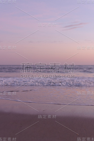 日落时，平静的海浪在海滩上翻滚