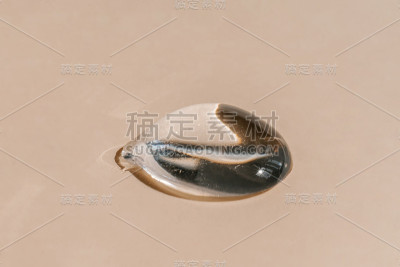 米色背景上的一滴透明化妆品凝胶。
