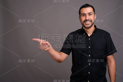 摄影棚里的波斯商人穿着黑色衬衫，背景是灰色