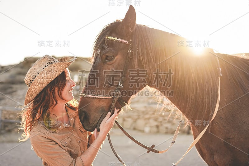 年轻的农民妇女与她的无咬的马在一个阳光明媚的一天内畜栏牧场-关于人与动物之间的爱的概念-关注女孩的脸