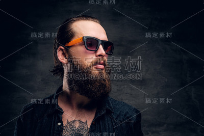 戴着墨镜的大胡子男子在黑暗的照相馆为摄影师摆姿势。
