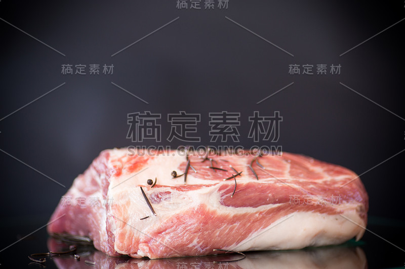 猪肉块生肉与香料和迷迭香在深色