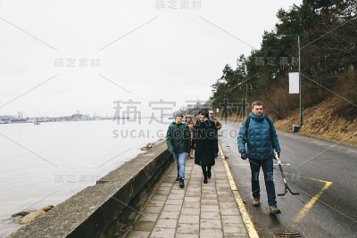 在寒冷的冬天，一家人穿着冬装走在海边的街道上——爷爷奶奶、爸爸、儿子