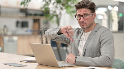 严肃的中年男子与笔记本电脑显示拇指向下