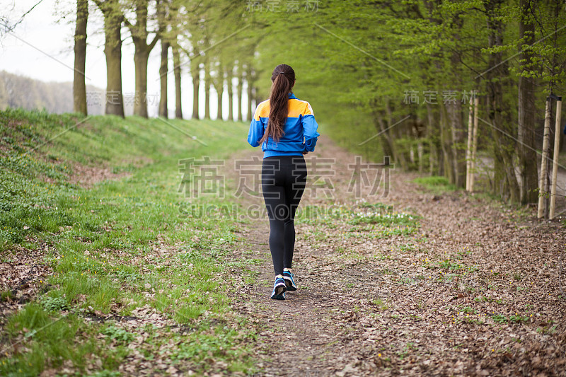 年轻漂亮的女人在小道上奔跑