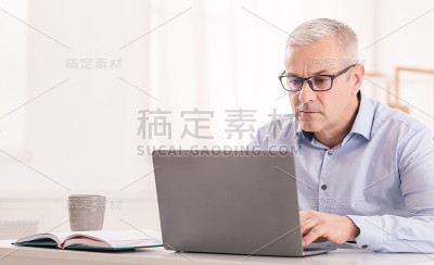 一个严肃的高级职员在办公室用笔记本电脑