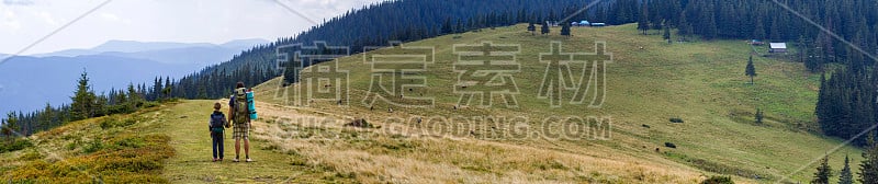 父子俩背着双肩包在风景秀丽的夏日青山里徒步旅行。爸爸和孩子站在一起欣赏山景。积极的生活方式，家庭关系