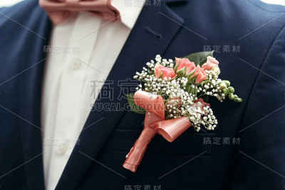 时尚的新郎或伴郎穿着粉红色的玫瑰胸花和领结摆姿势，准备在早上举行婚礼