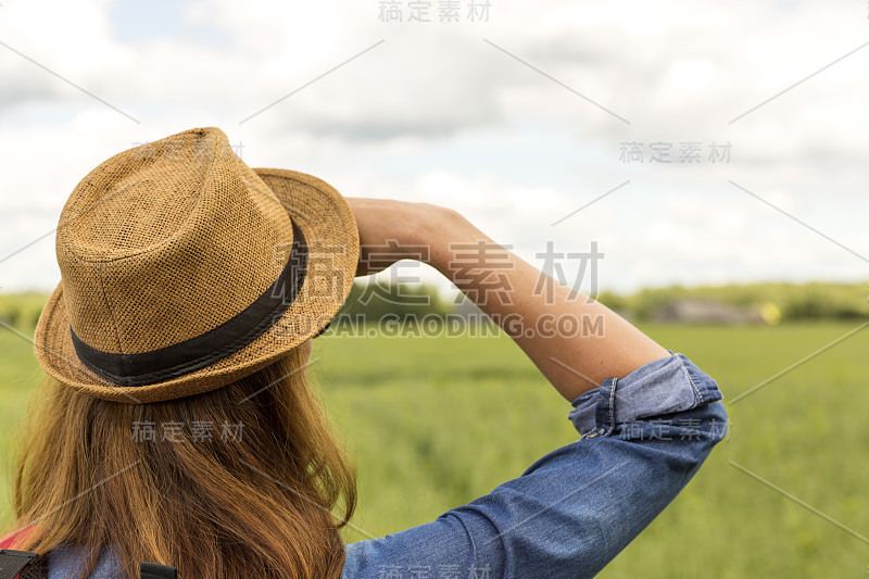 戴着帽子的女人俯瞰着草地，户外活动，徒步旅行