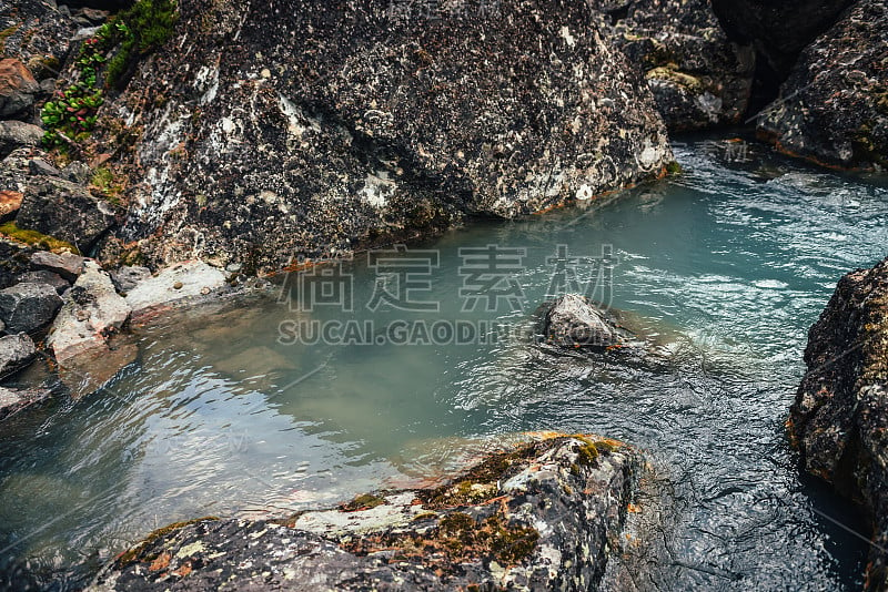 风景自然背景绿松石清澈的水溪之间的岩石与苔藓和地衣。大气的山地景观与苔藓石透明的山溪。美丽的山流。