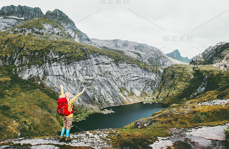 快乐的女人举起双手，背着背包在挪威山区的湖边徒步旅行