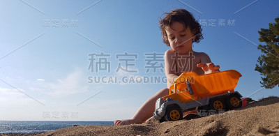 一个小男孩在海滩上玩玩具卡车