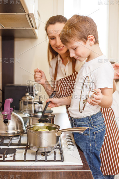 小男孩和他的妈妈在锅上做饭