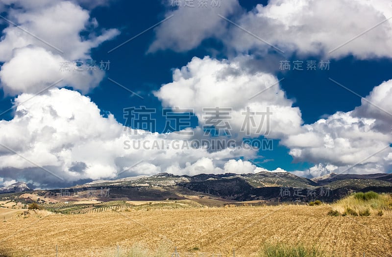 山景上的蓝色多云的天空背景。风景如画的群山在阳光下闪闪发光。令人屏息的自然影像