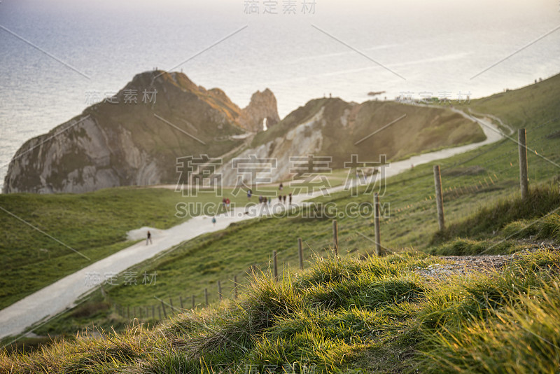 生机勃勃的日落在海上堆叠景观在英国海岸在春天与游客在小路上