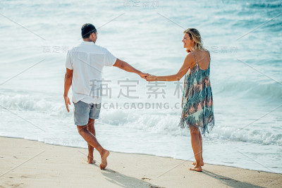 快乐的情侣一起在夏天的海滩上散步
