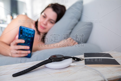 女人上网手机躺在床上智能手表上无线充电器